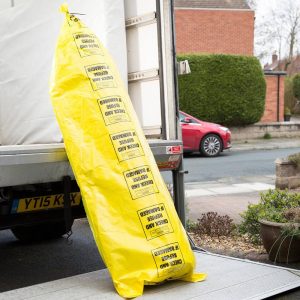Yellow rug storage bag with rug rolled up inside, ready to be put inside a removals van